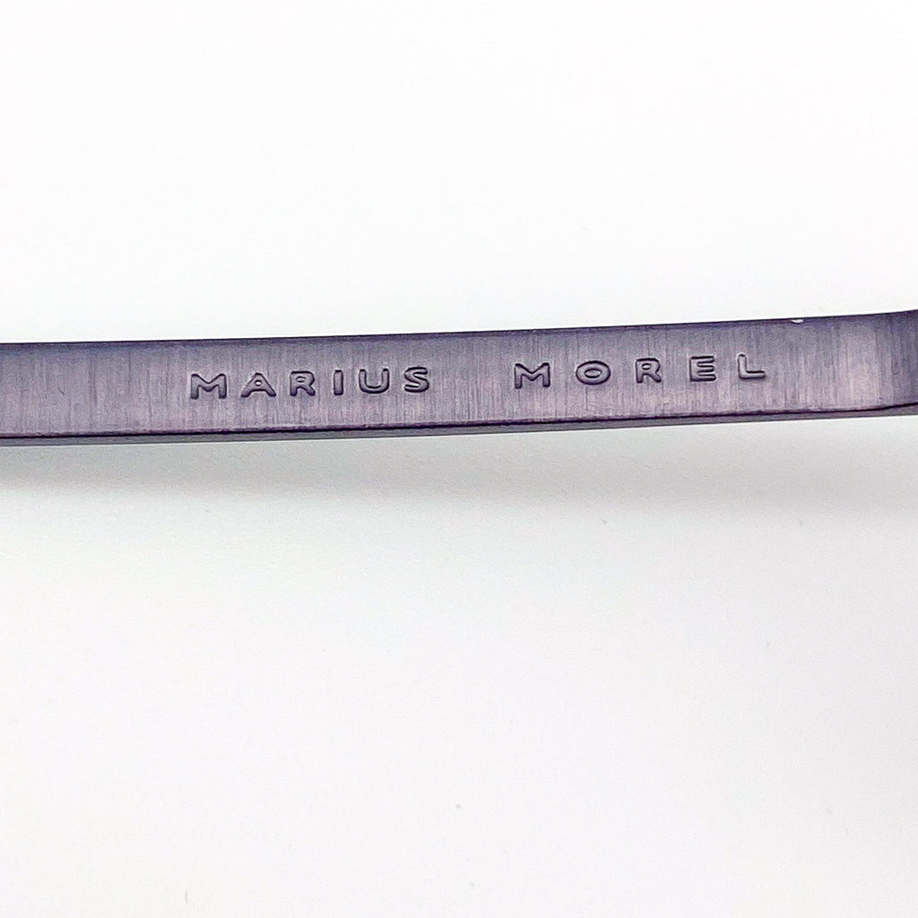 Metallic eyeglass temple arm with 'Marius Morel' engraving on a white background