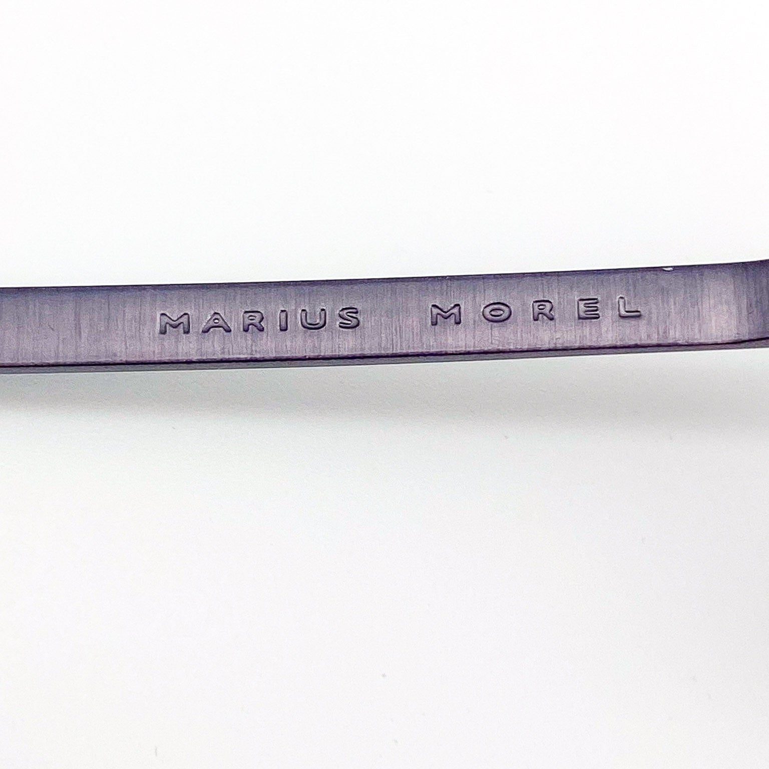 Metallic eyeglass temple arm with 'Marius Morel' engraving on a white background