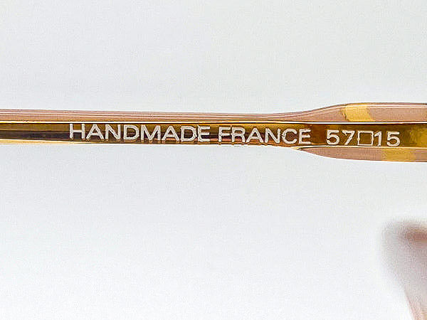 Close-up of eyeglasses with 'Handmade France' engraving on a white background