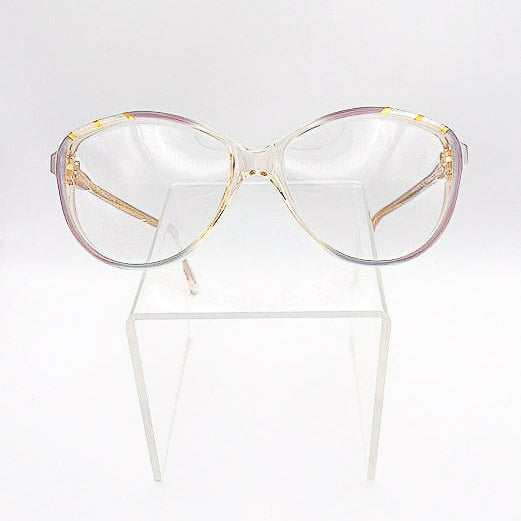 1980s clear and gold-framed eyeglasses on a white stand with a white background