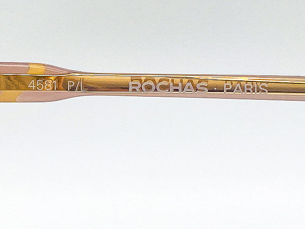 Gold eyeglass frame with 'Rochas Paris' branding on a white background