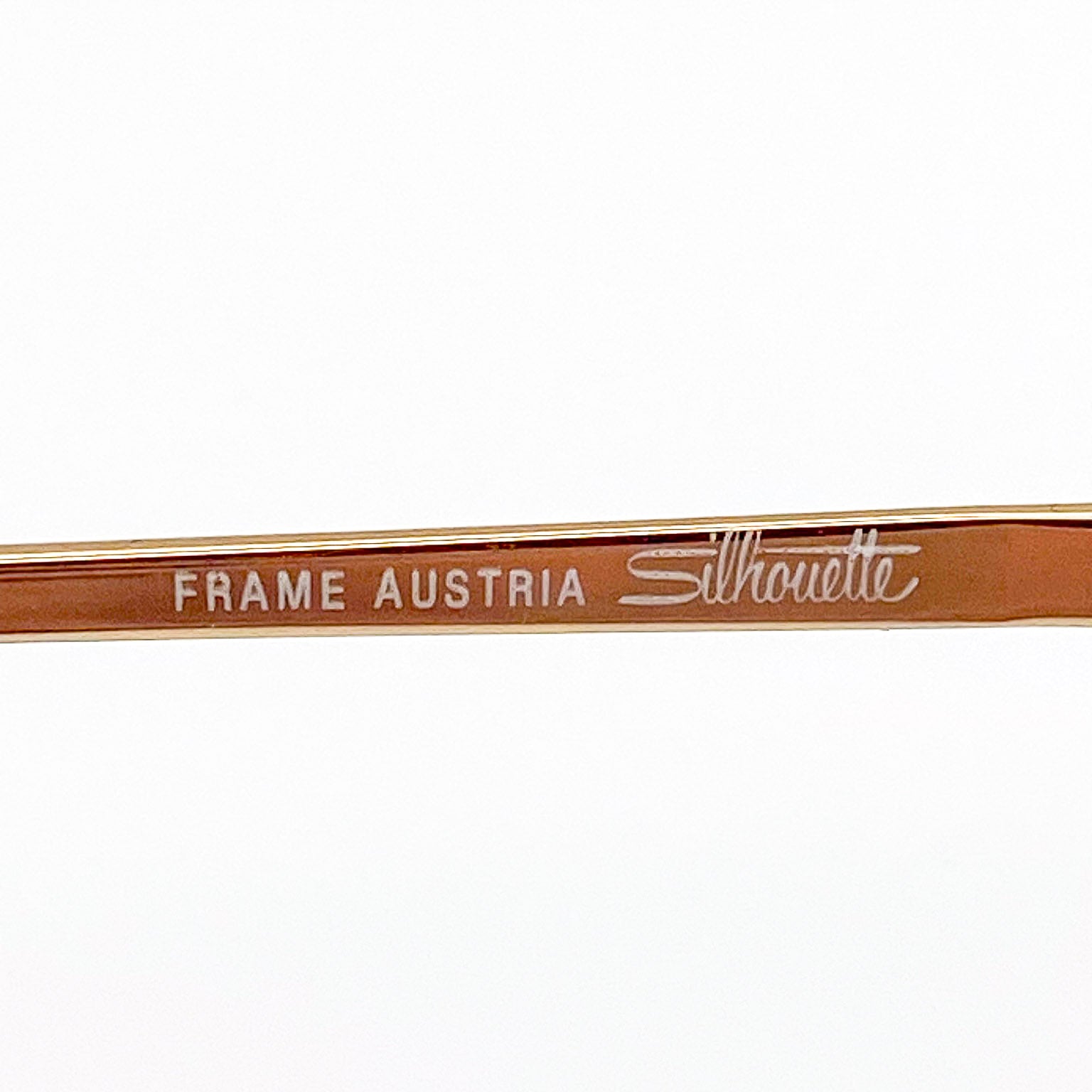 Gold Silhouette eyeglasses temple stem with 'Frame Austria' text