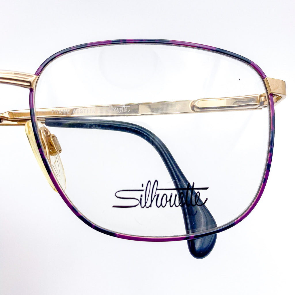 Purple, black, and gold eyeglasses with 'Silhouette' branding