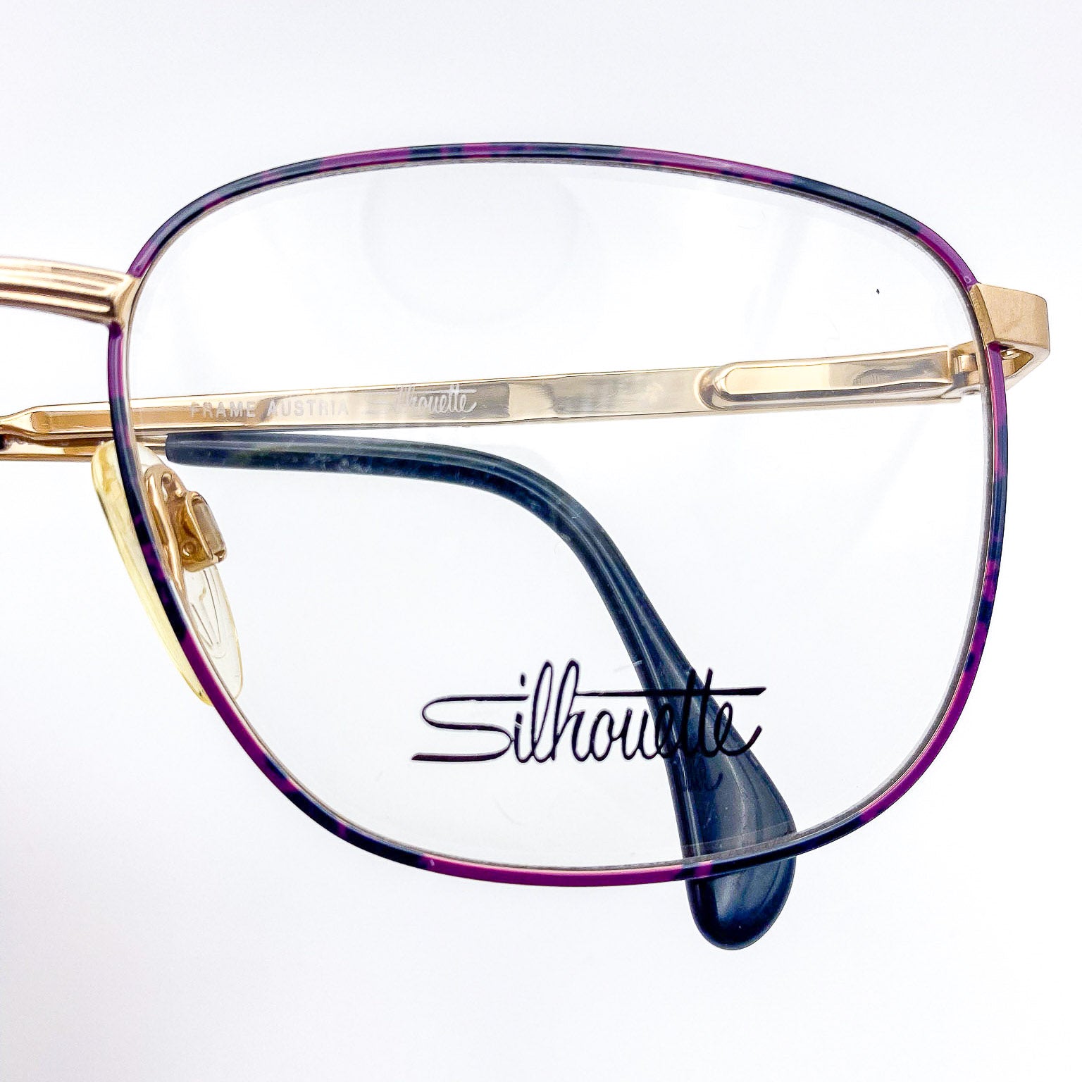 Purple, black, and gold eyeglasses with 'Silhouette' branding