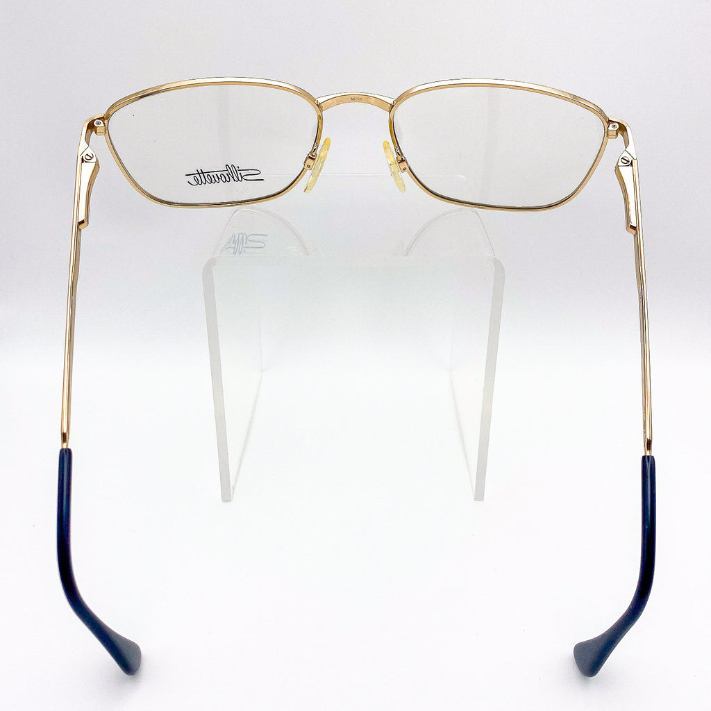 vintage 1990s Silhouette gold eyeglasses frames on a clear stand