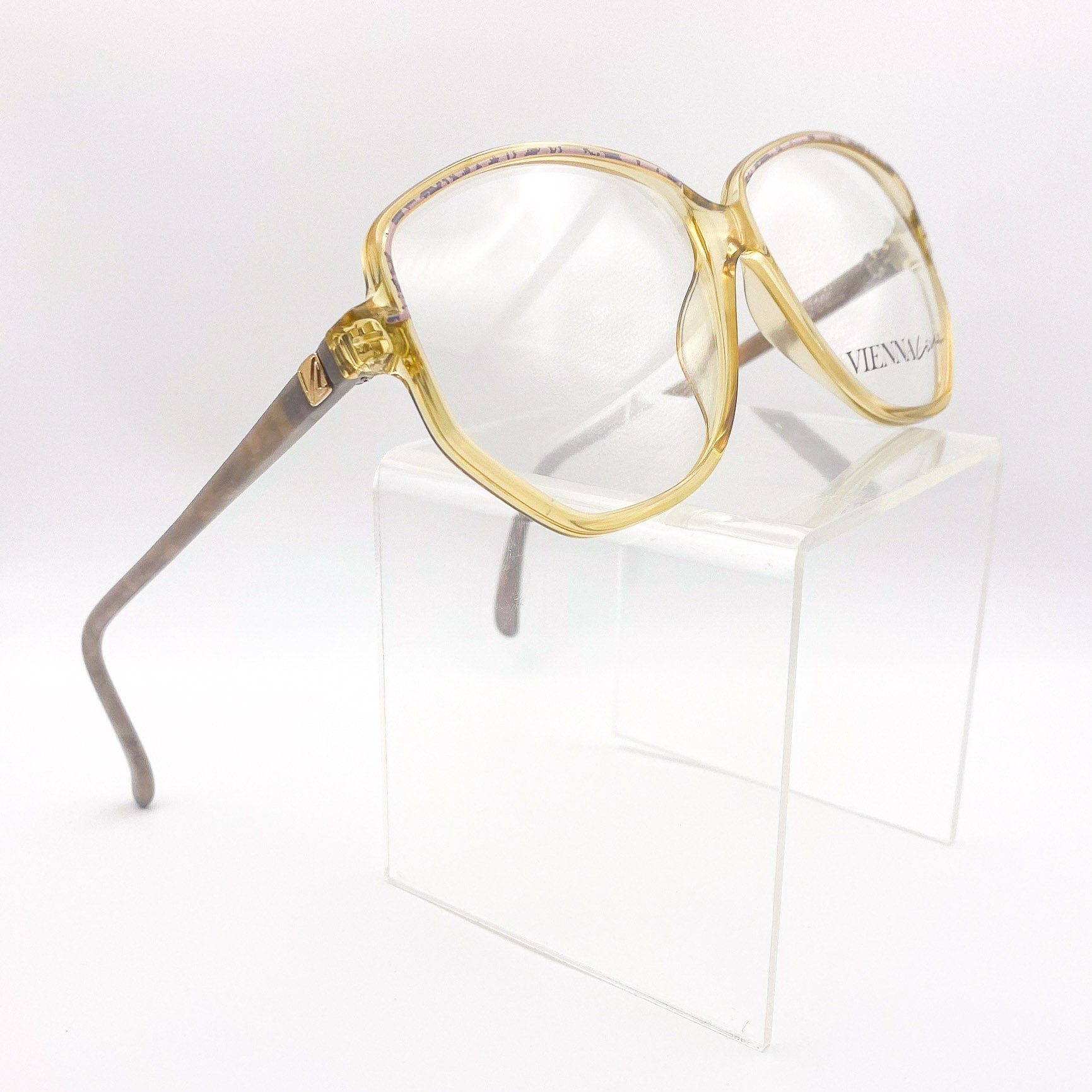 Oversized grandma eyeglasses on a clear stand against a white background