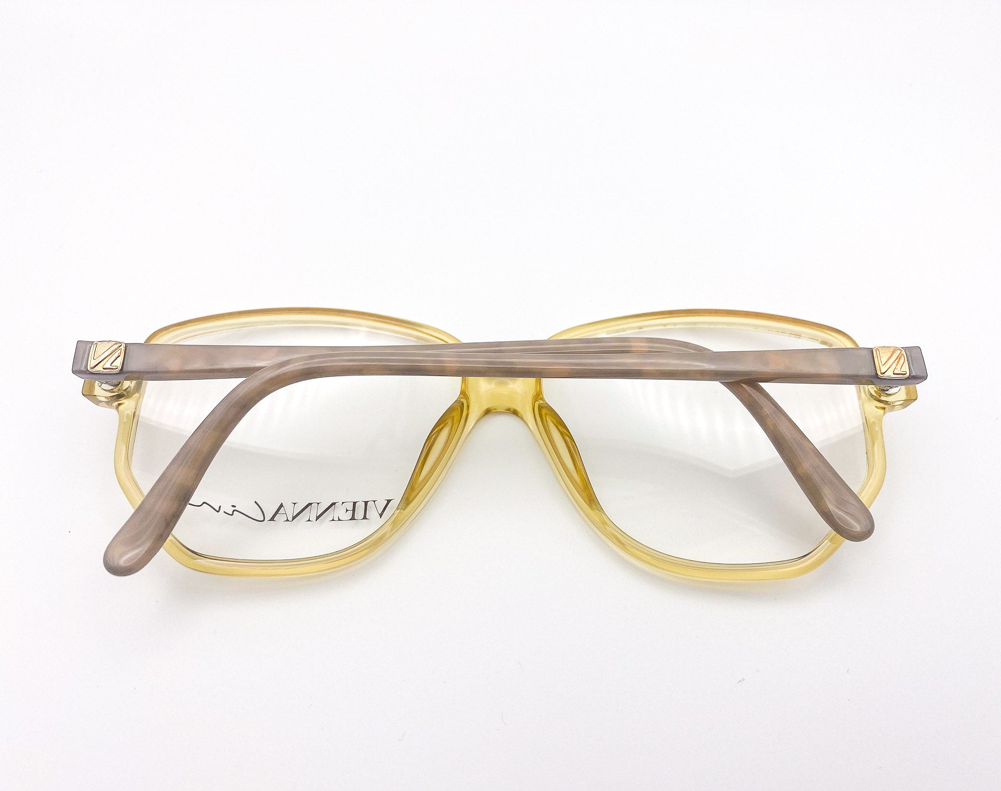 1970s Optyl eyeglasses with translucent yellow frame and beige temples on a white background