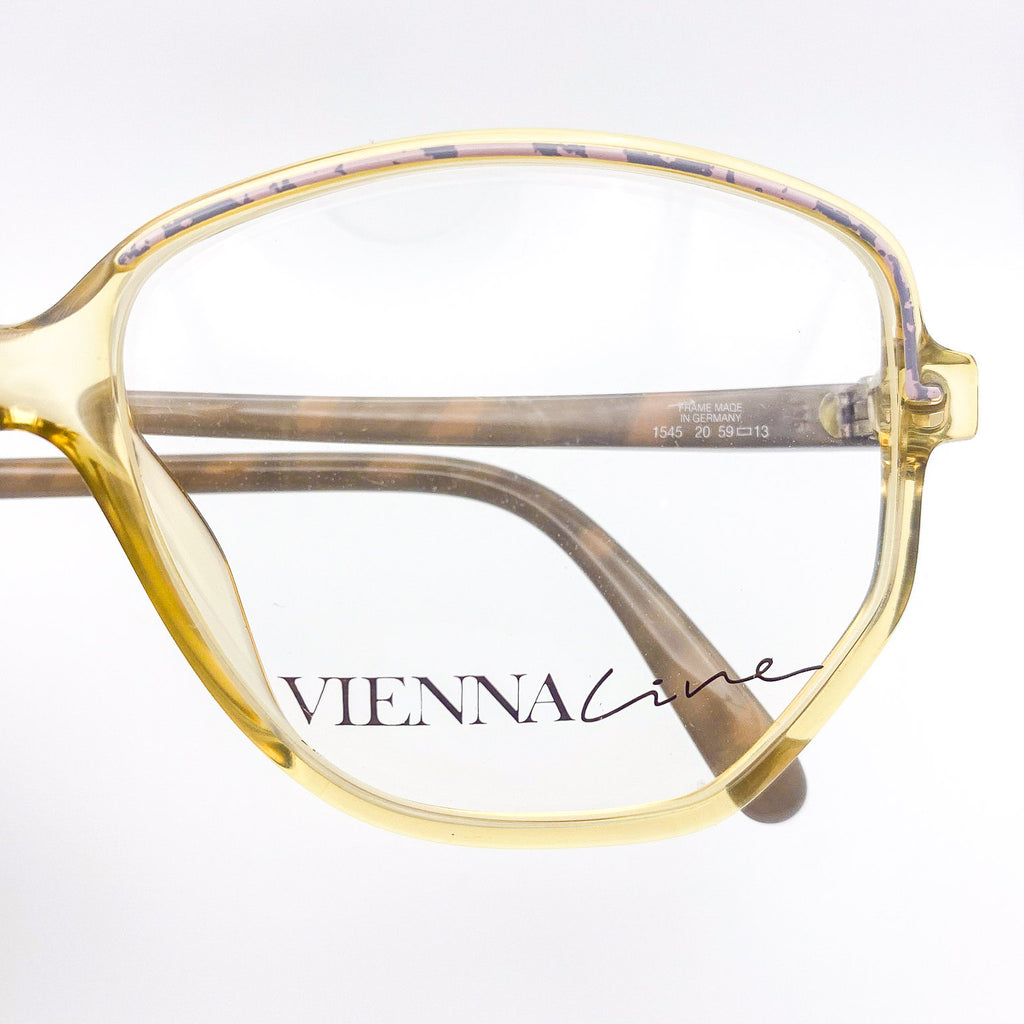 Gold-framed eyeglasses with 'VIENNA LINE' branding on a white background