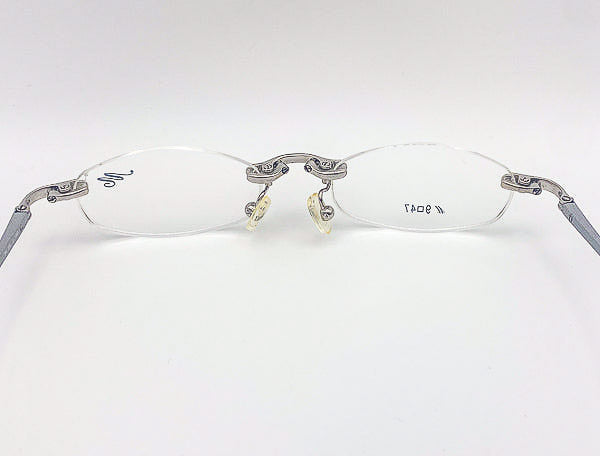 Pair of rimless eyeglasses with decorative metal frames on a white background