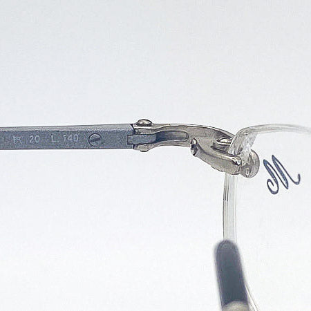 Close-up of a pair of eyeglasses with a visible 'M' brand logo on a white background
