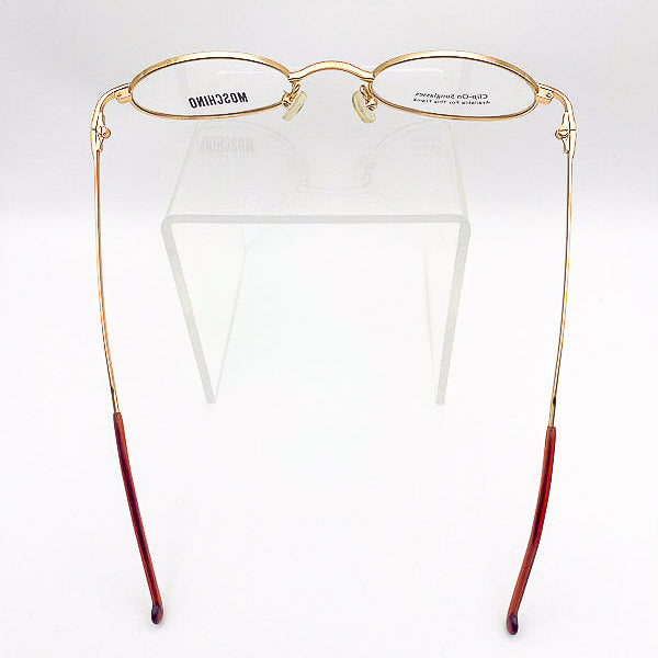 Gold-framed eyeglasses with red arms on a white background