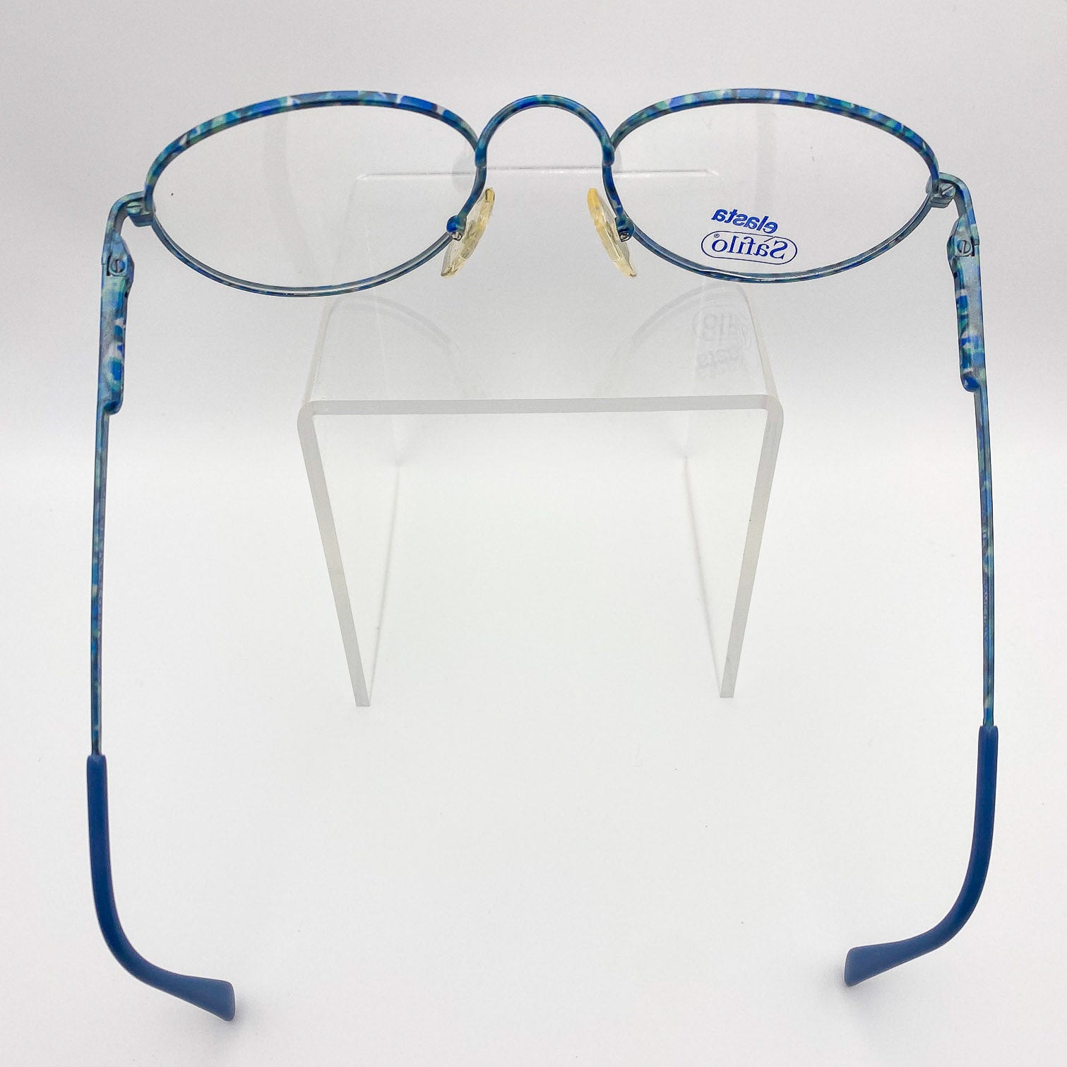 Blue eyeglasses on a clear stand against a white background