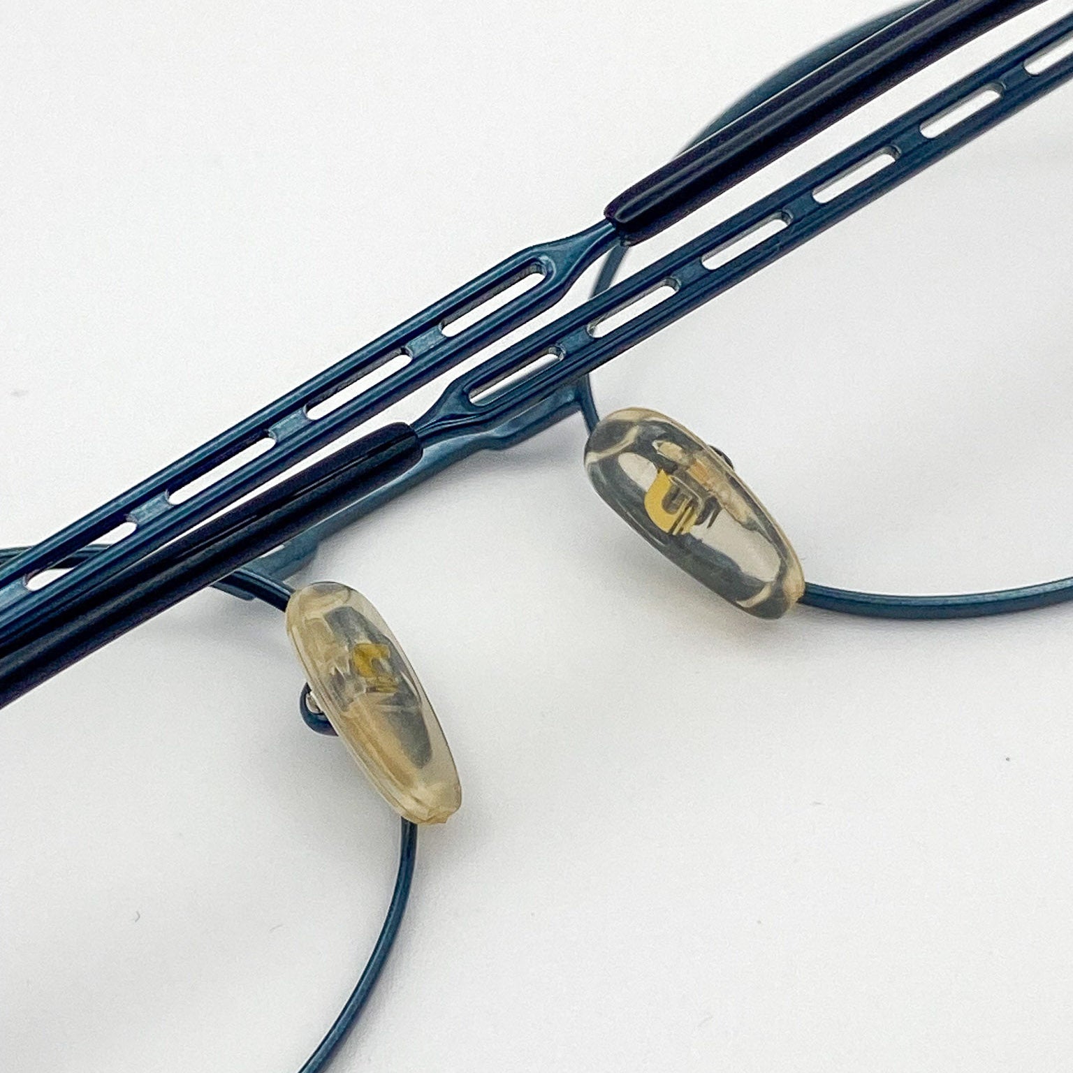 Close-up of a teal metal eyeglass frame on a white background