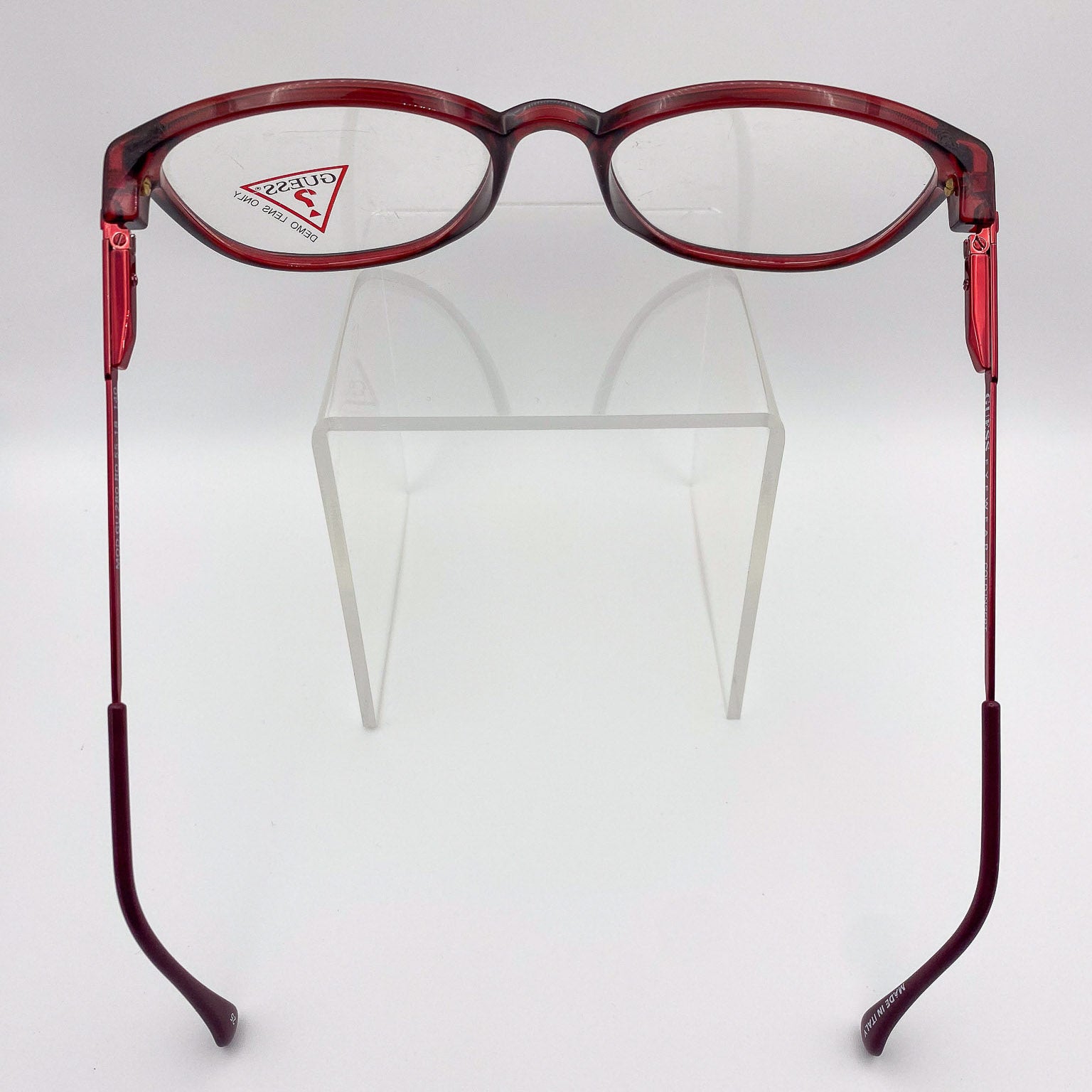 Red eyeglasses on a clear stand against a white background