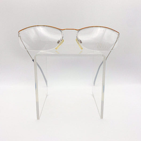 Vintage semi-rim eyeglasses with gold frames on a white stand against a white background