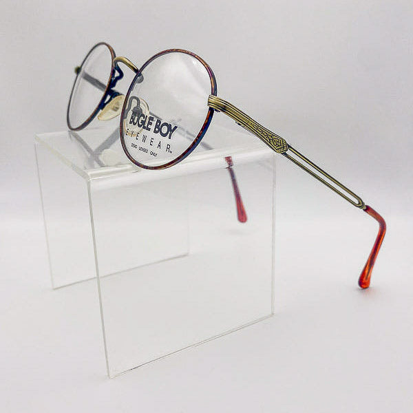 Eyeglasses with tortoiseshell arms on a clear stand against a white background