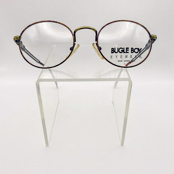 Round eyeglasses with gold accents on a clear stand against a white background, branded 'Bugle Boy Eyewear'.