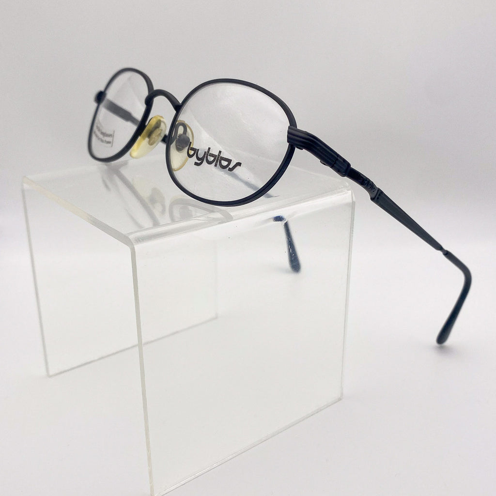 Eyeglasses with black frame on a clear stand against a white background