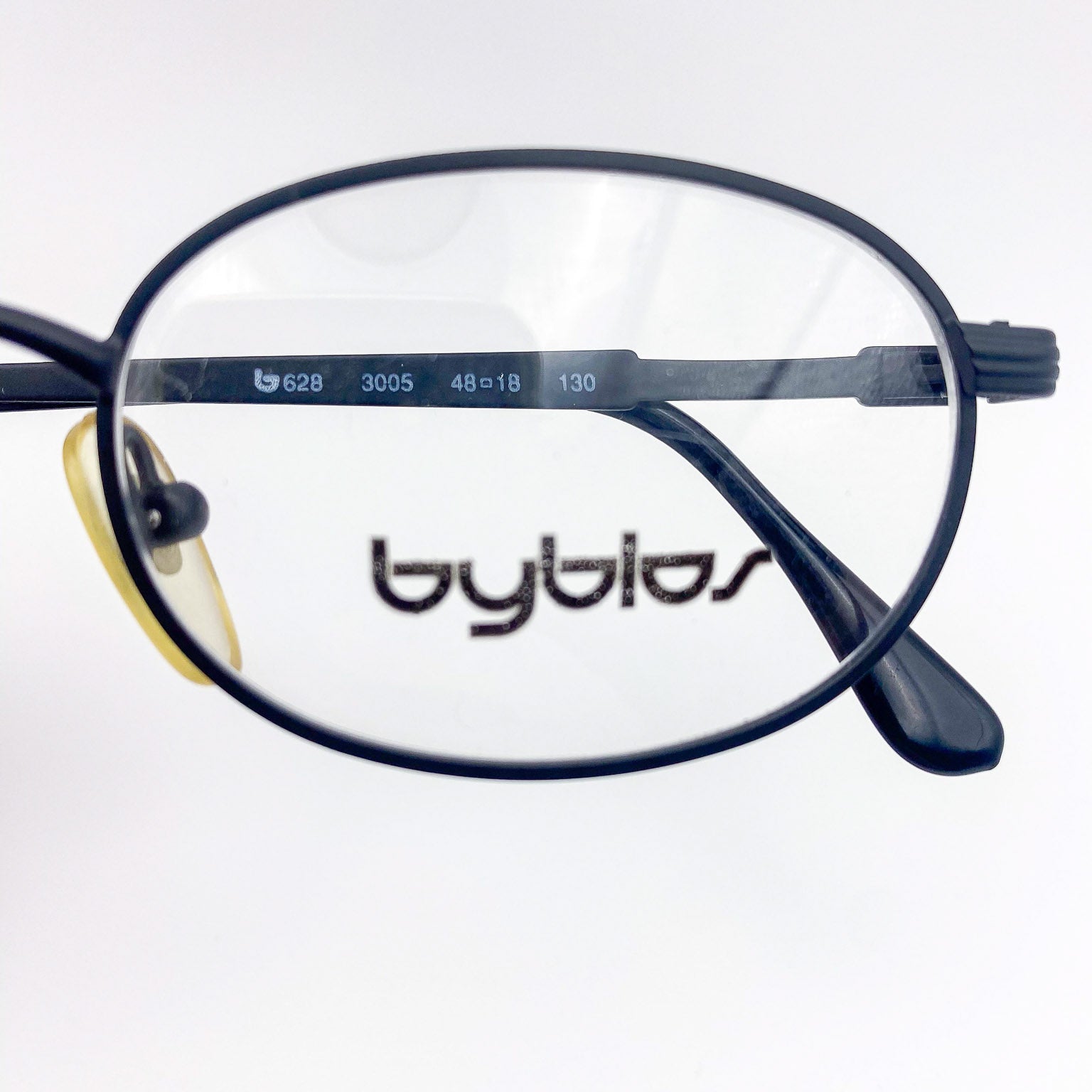 Close-up of eyeglasses with 'byblos' branding on a white background