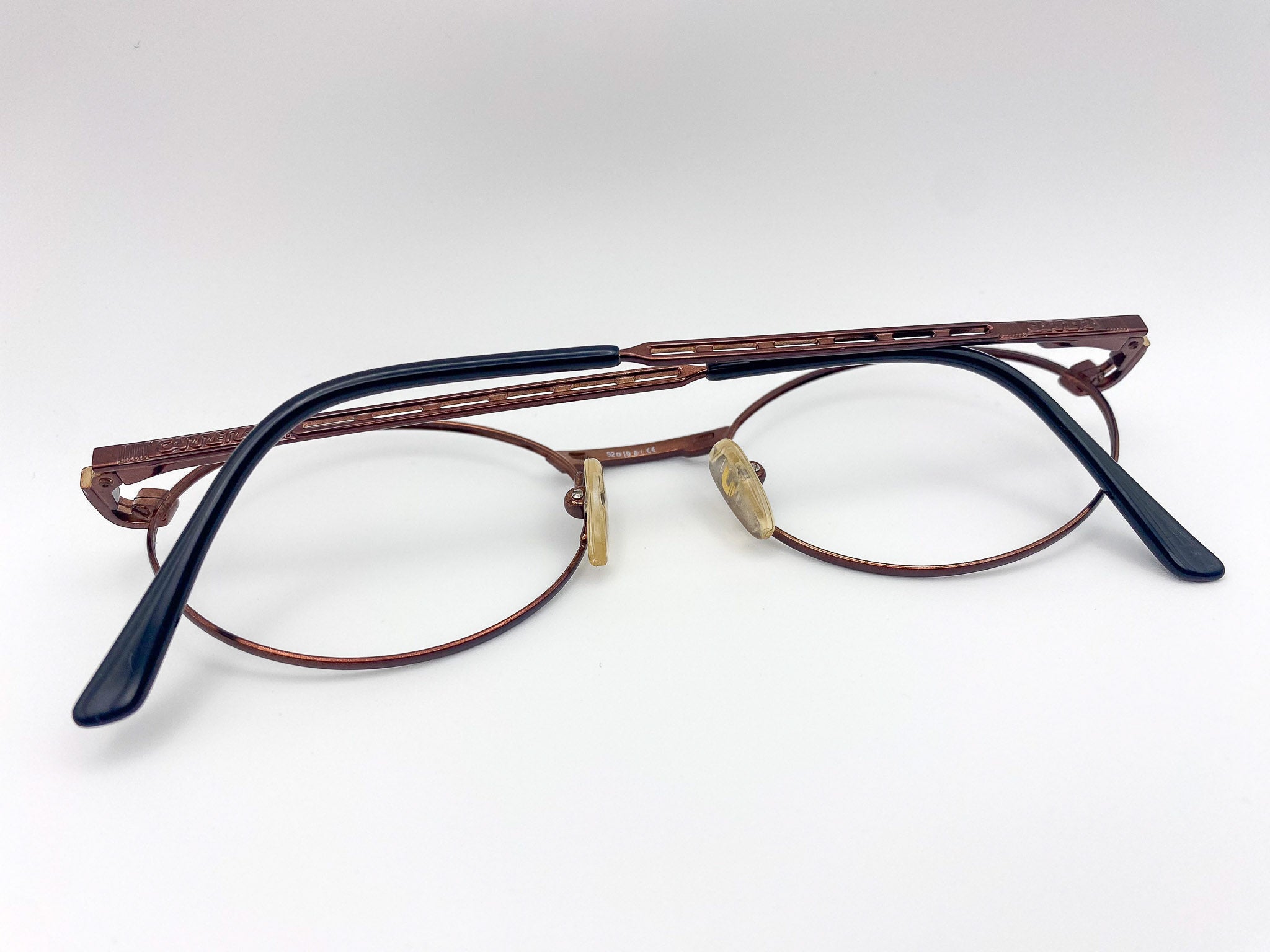 Pair of eyeglasses with a metallic burgundy frame and black arms on a white background
