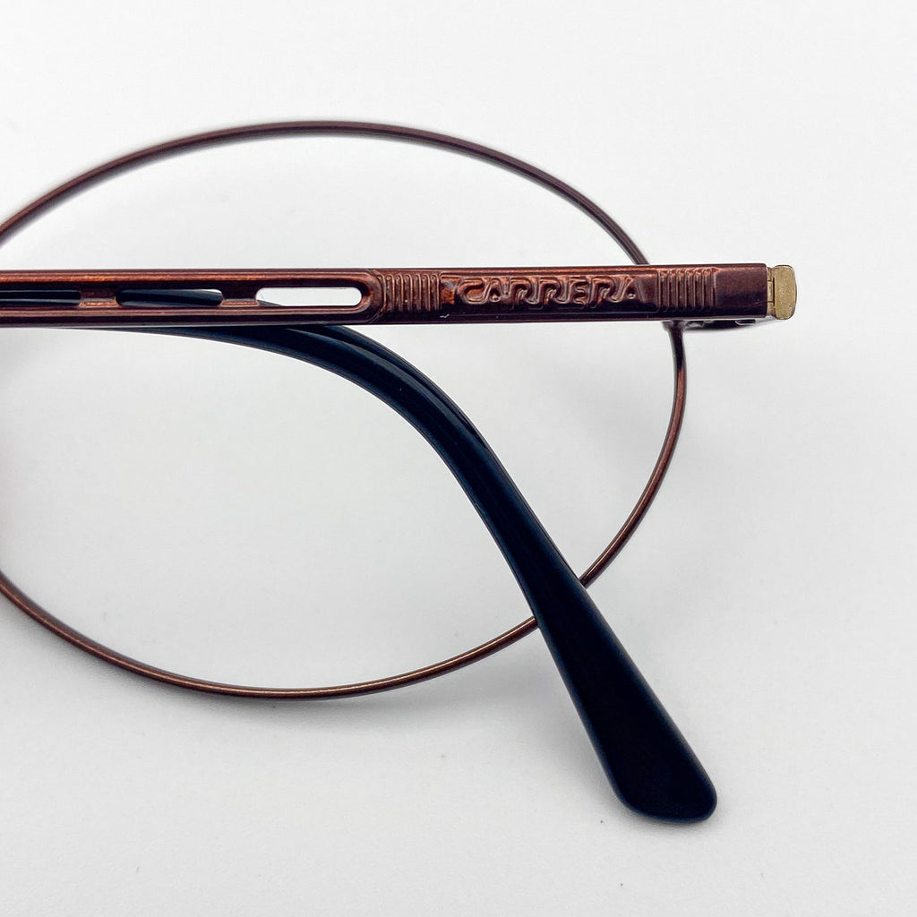 Close-up of a pair of eyeglasses with 'Carrera' branding on the frame.