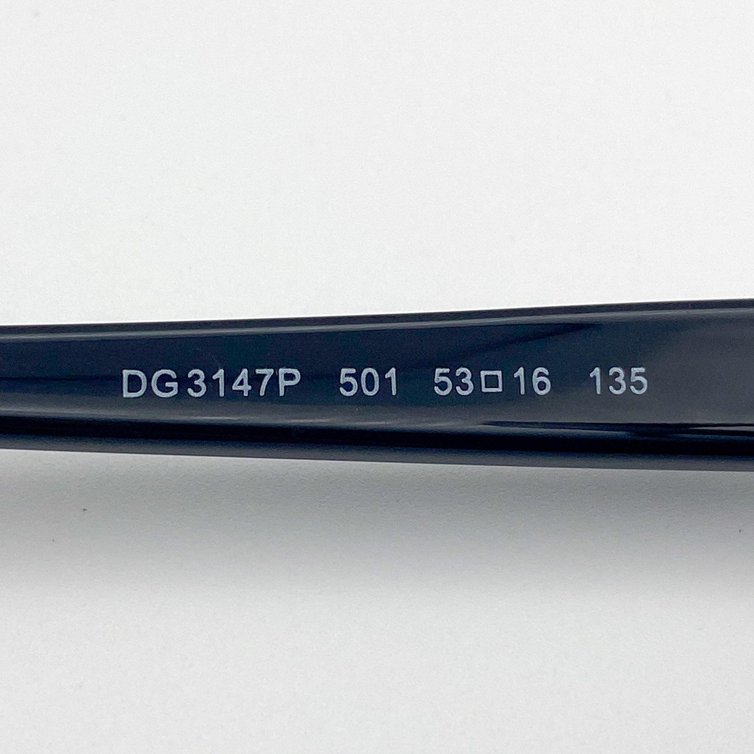 Close-up of a black eyeglass frame with serial number on a light gray background