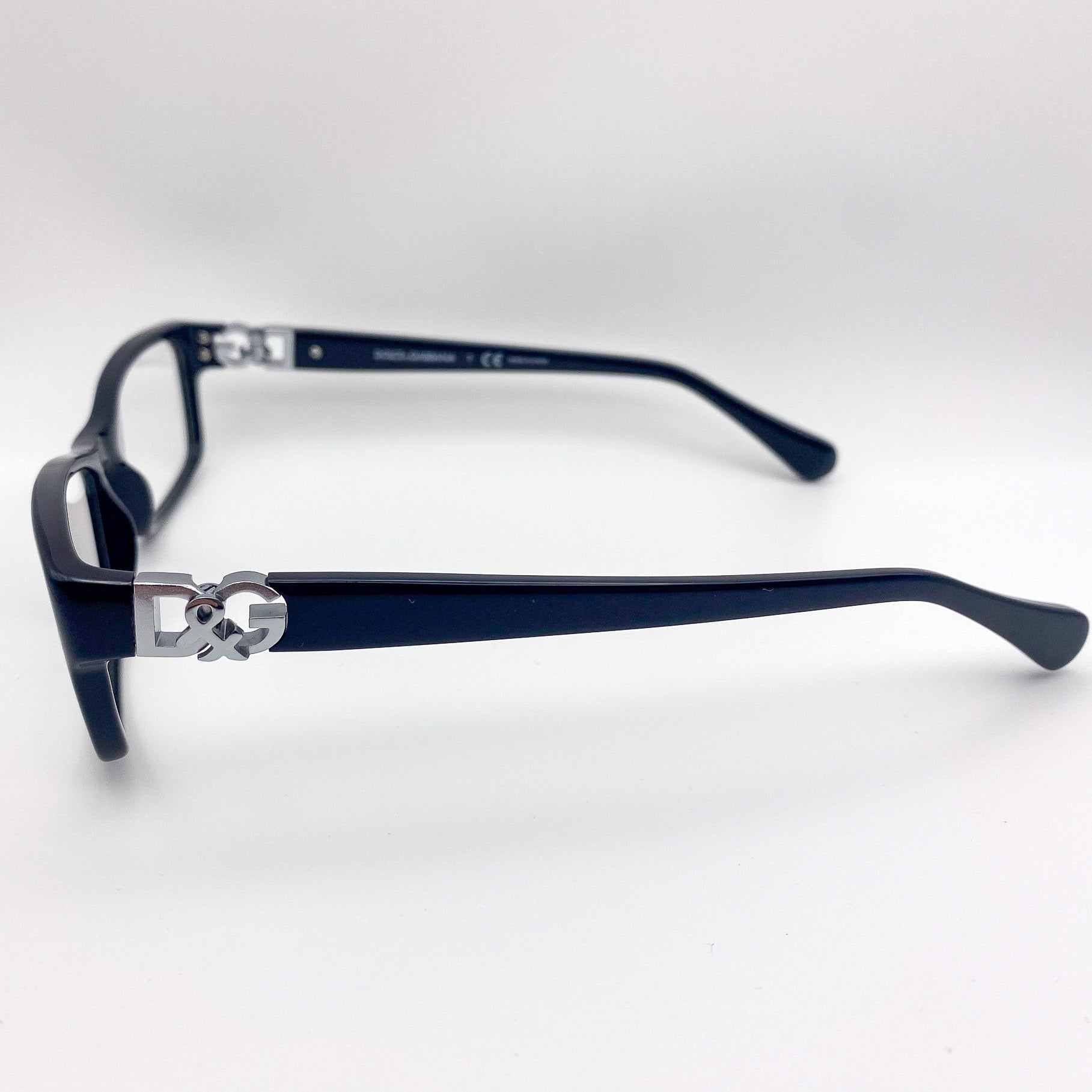 Black rectangular eyeglasses with a silver logo on a white background