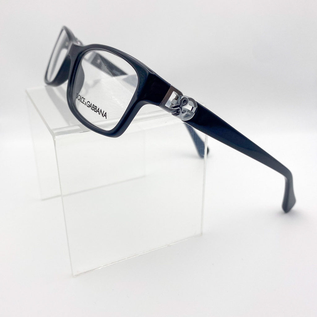 Black Dolce & Gabbana eyeglasses on a clear stand against a white background