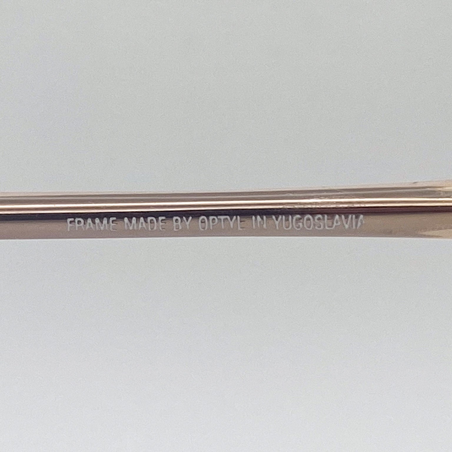 Eyeglass frame with 'Frame made by Optyle in Yugoslavia' engraving on a light gray background