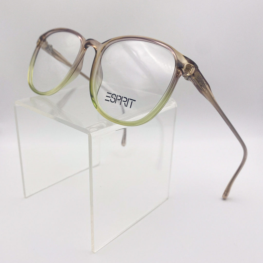 Brown and green fade eyeglasses with 'Esprit' logo on a clear stand against a white background