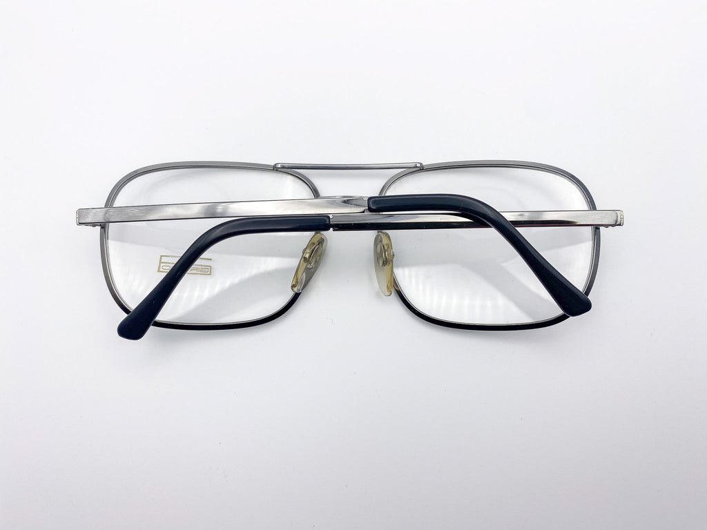 1980s silver eyeglasses with black arms on a white background