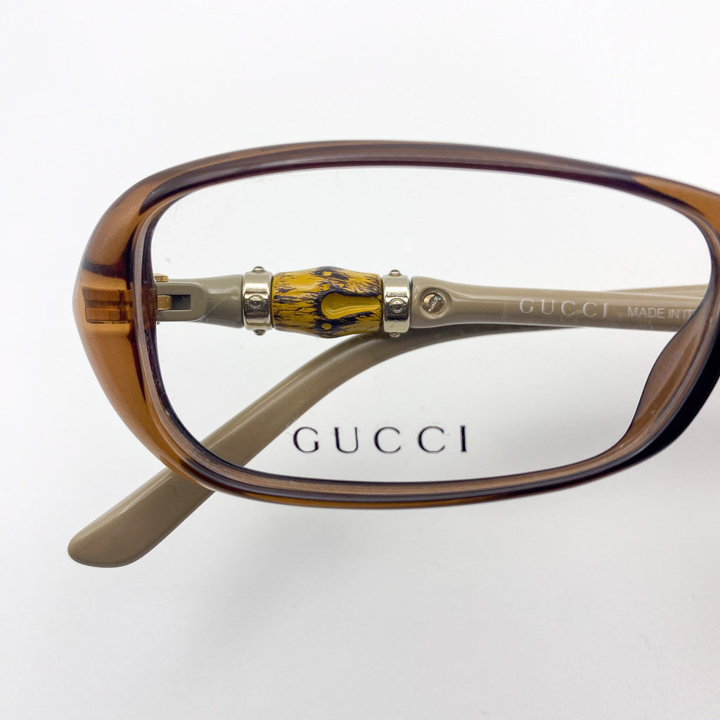 Gucci eyeglasses with a brown frame and decorative arm on a white background