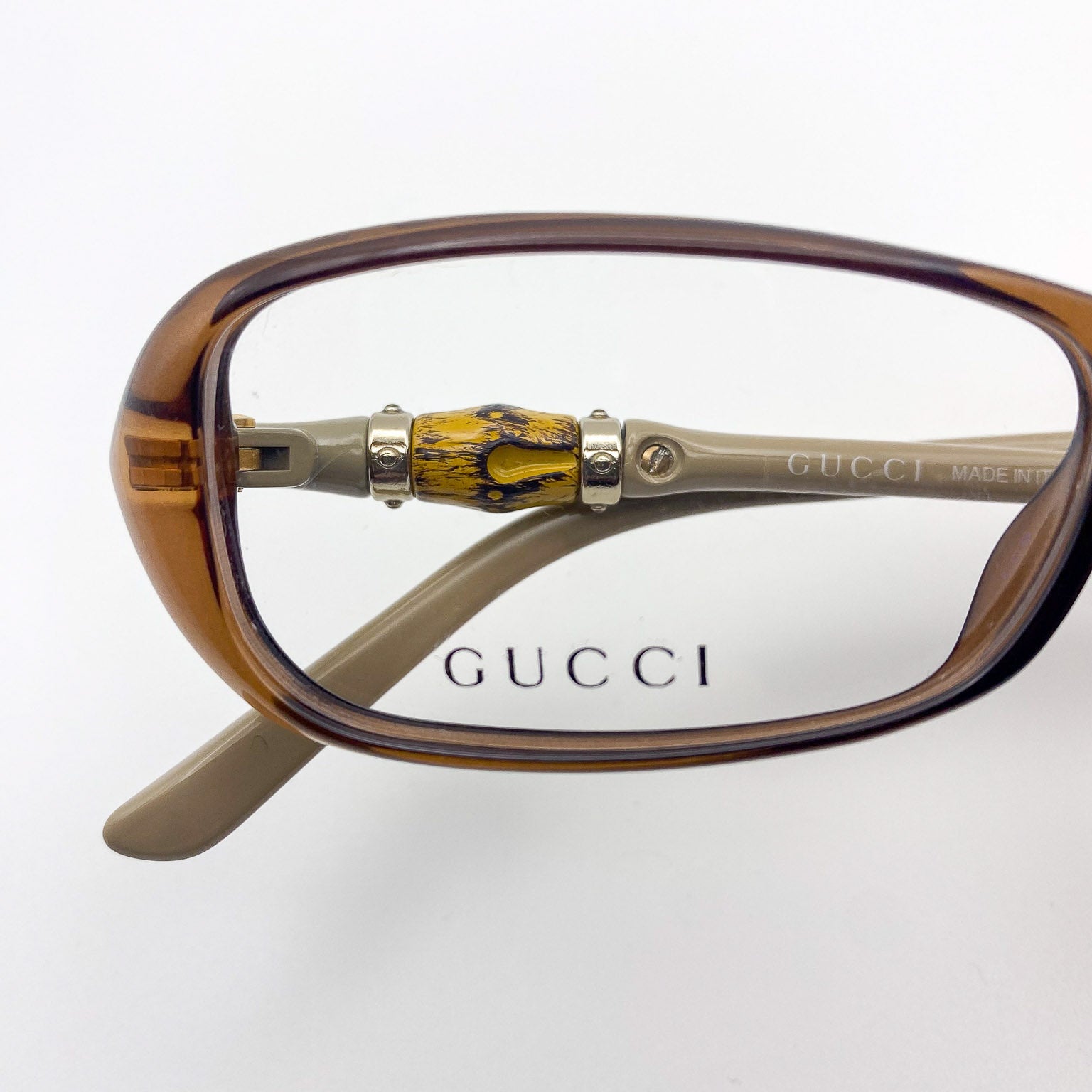 Gucci eyeglasses with a brown frame and decorative arm on a white background