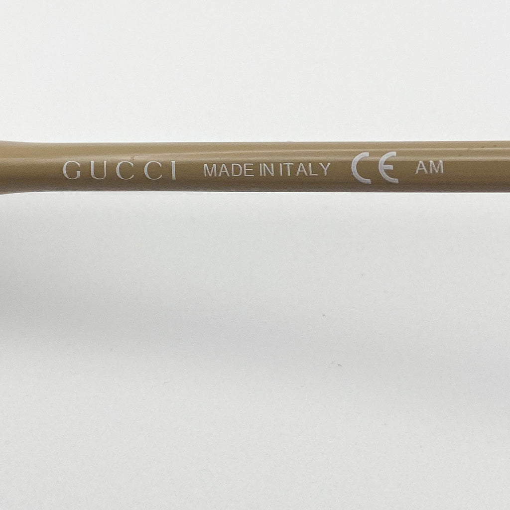 Close-up of a Gucci frame with 'Made in Italy' and CE logo on a beige background