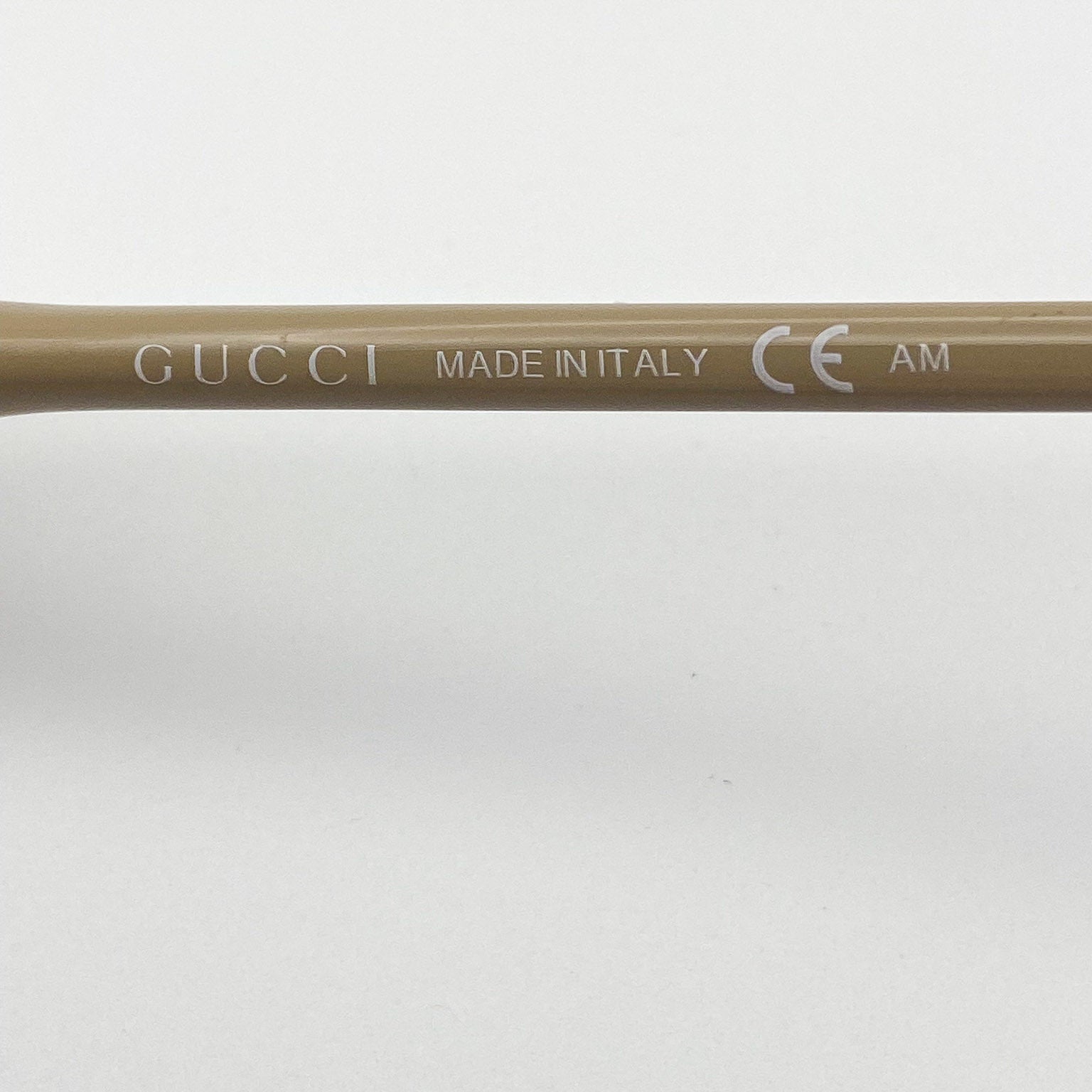 Close-up of a Gucci frame with 'Made in Italy' and CE logo on a beige background