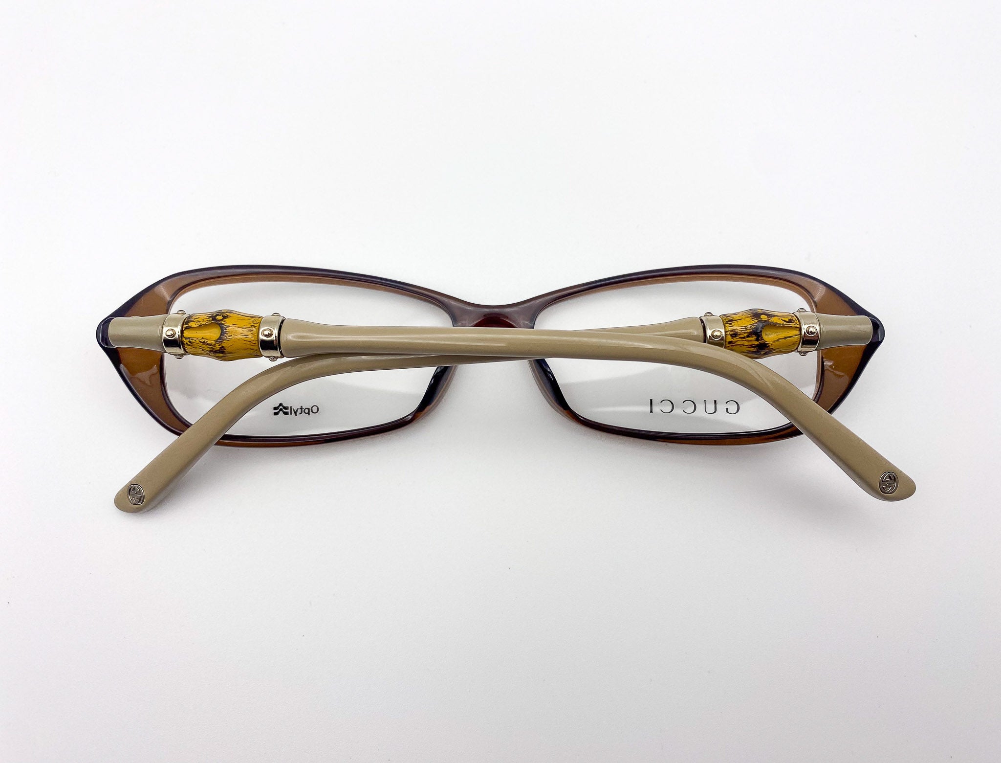 Gucci eyeglasses with brown frame and gold accents on a white background