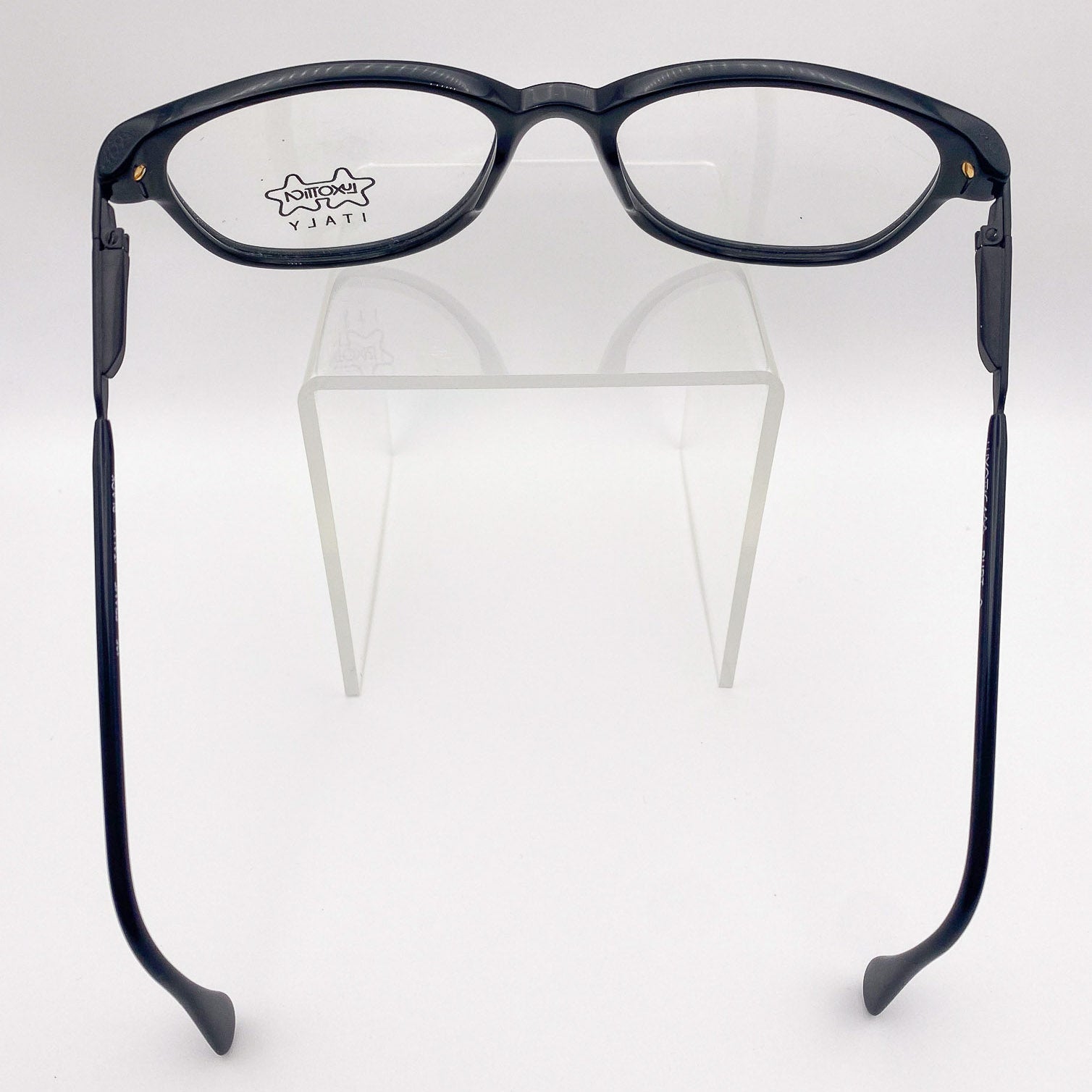 Black eyeglasses on a clear stand against a white background