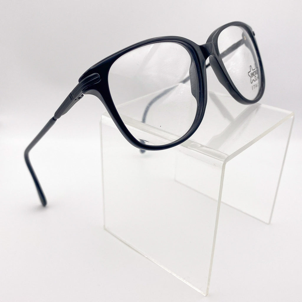 Black eyeglasses on a clear cube against a white background