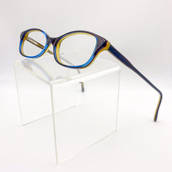 Blue and brown eyeglasses on a clear stand against a white background