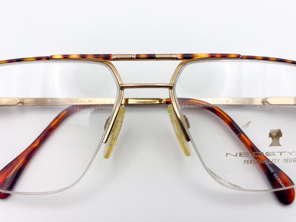 Tortoiseshell eyeglasses with gold frame and 'Neostyle' branding on a white background