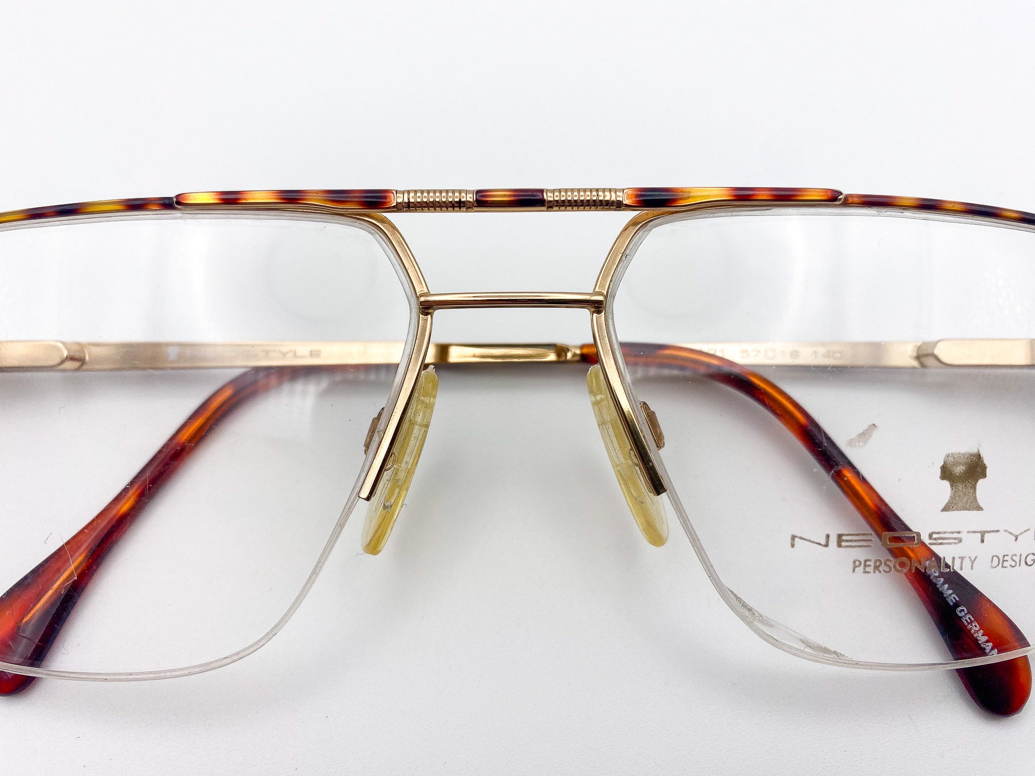 Tortoiseshell eyeglasses with gold frame and 'Neostyle' branding on a white background
