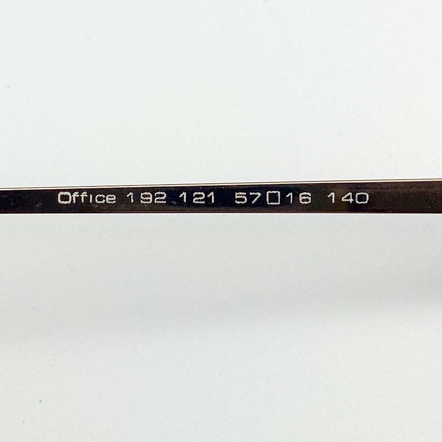 Close-up of an eyeglass frame with 'Office' text on a white background
