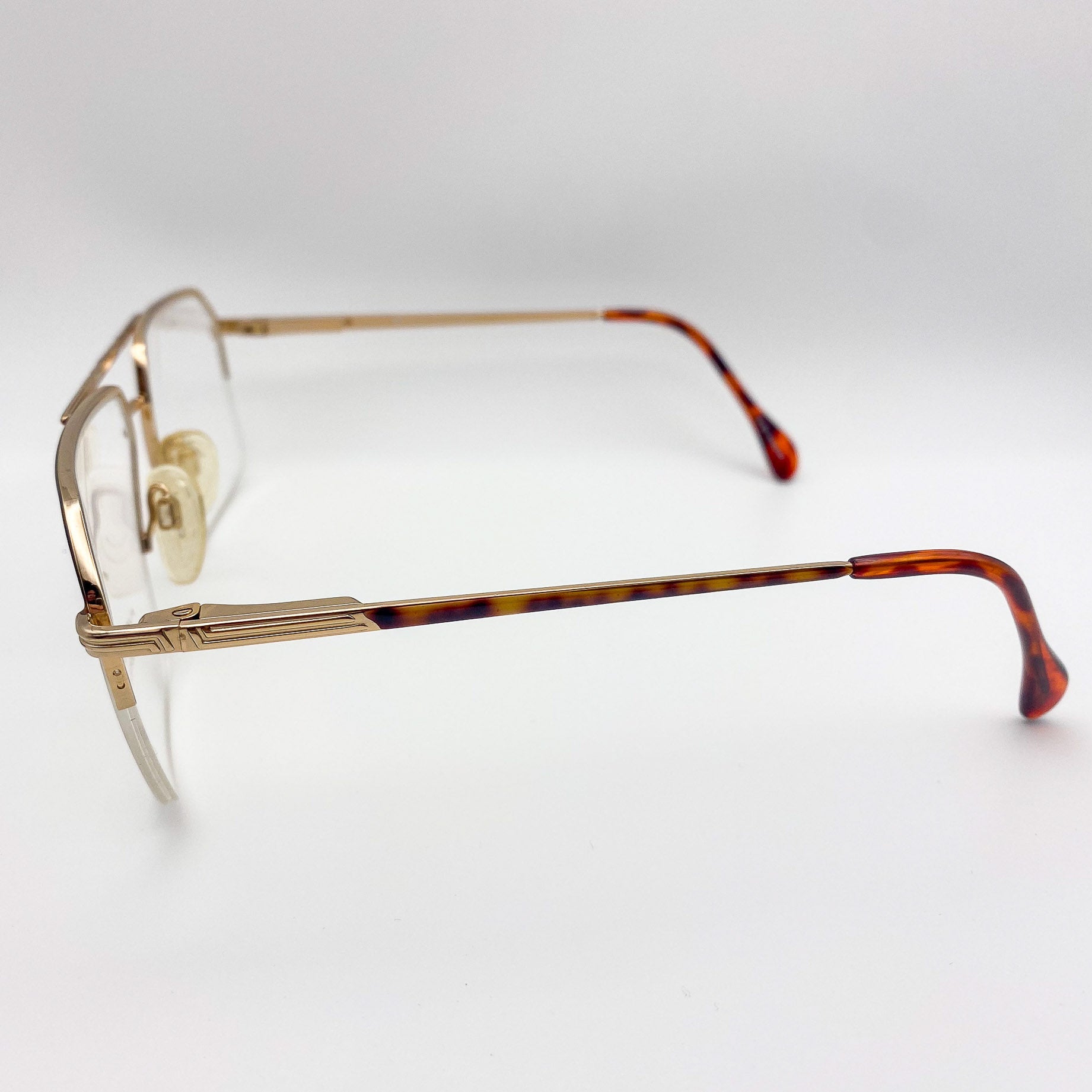 Aviators with a gold frame and tortoiseshell arms on a light gray background