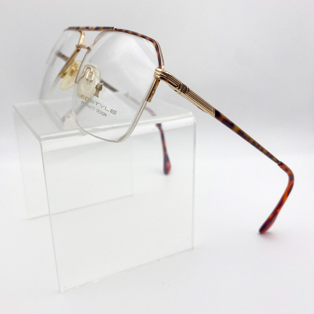 Navigator eyeglasses with tortoiseshell frame on a clear stand against a white background
