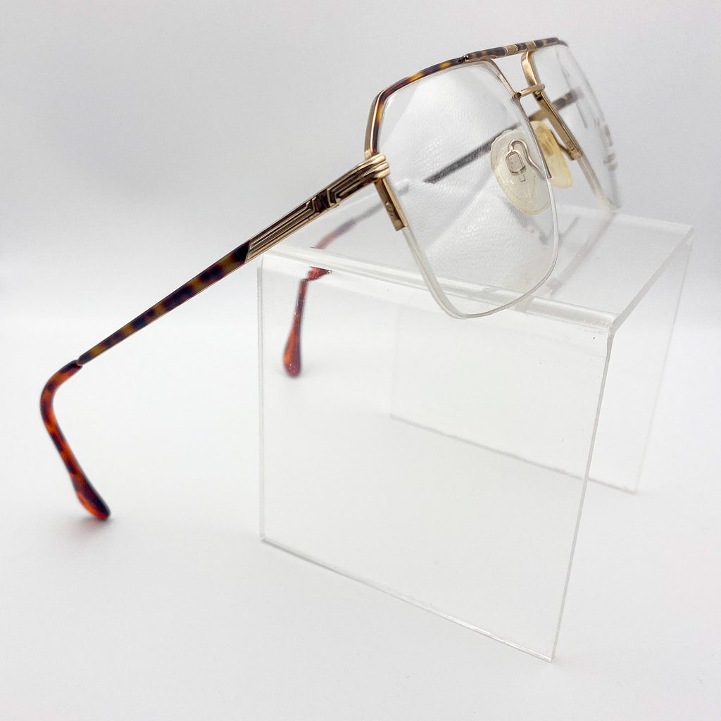Vintage Neostyle glasses with a tortoiseshell frame on a clear stand against a white background