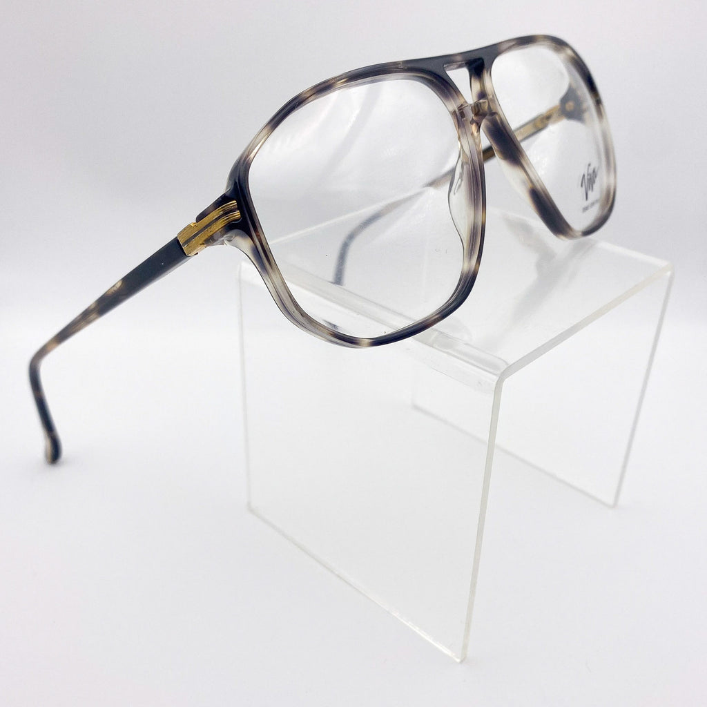 Tortoiseshell eyeglasses on a clear stand against a white background
